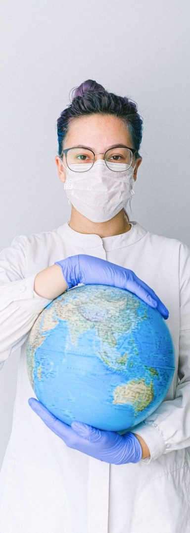 Médecin tenant un globe terrestre avec des gants et un masque FFP2